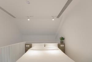 a white bedroom with a large bed with white sheets at Lloyd's Inn in Singapore