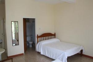 a bedroom with a bed and a bathroom with a toilet at The Relax Inn in Saint Georgeʼs