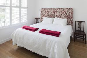 a white bed with two red pillows on it at The Cottage at Bolobek in Macedon