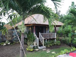 una piccola casa con una palma di fronte di The Jingga Villas a Nusa Lembongan