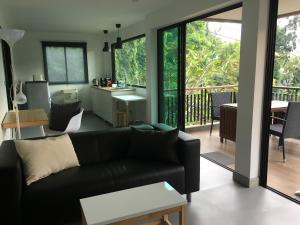 a living room with a black couch and a kitchen at Baan Andaman Sea Surf in Patong Beach