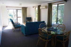 uma sala de estar com um sofá azul e uma mesa e cadeiras em Jadon Place Holiday Apartments em Gold Coast