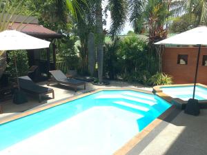 a swimming pool with two chairs and an umbrella at Baan Andaman Sea Surf in Patong Beach