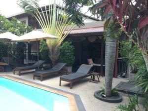 巴東海灘的住宿－班安達曼海衝浪酒店，毗邻度假酒店的带椅子和遮阳伞的游泳池
