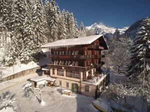 a large building in the snow with snow covered trees at Hotel Bellary in Grindelwald