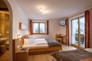 a bedroom with a bed and a table and windows at Ferienhof Stadlpoint in Ried im Zillertal