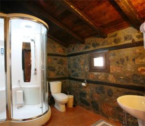 a stone bathroom with a toilet and a sink at Grand House Suites in Palaios Agios Athanasios