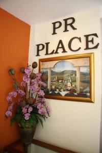un jarrón con flores y una foto en la pared en PR Place Hotel en Bangkok