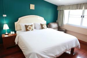 a bedroom with a white bed and a green wall at PR Place Hotel in Bangkok