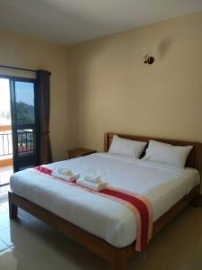 um quarto com uma cama grande com lençóis brancos e uma janela em Hill Top Home em Santikhiri