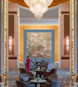 a woman standing in a room with tables and chairs at Shangri-La Shenyang in Shenyang