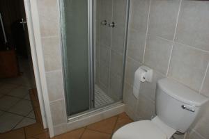 a bathroom with a toilet and a glass shower at Eric's Apartments in Centurion