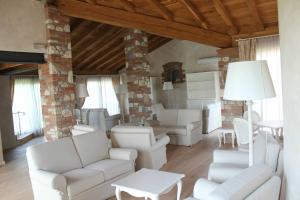 a living room with white furniture and a brick wall at Relais Mondotella in Pozzolengo