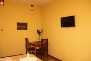 a dining room with a table and a television on the wall at Lily Bank Cottage in Nuwara Eliya