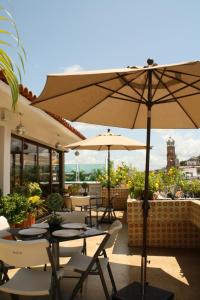 eine Terrasse mit Tischen, Stühlen und Sonnenschirmen in der Unterkunft Hotel Porto Allegro Puerto Vallarta in Puerto Vallarta