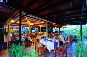 a restaurant with white tables and chairs and tablesearcher at Maleedee Bay Resort in Ao Nang Beach