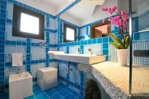 a blue tiled bathroom with a sink and a toilet at Residence L'Ea di Lavru - Appartamenti Mono-Bilo-Trilocali in Porto San Paolo