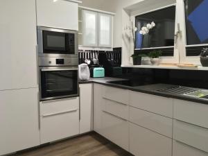 een keuken met witte kasten en zwarte aanrechtbladen bij Moderne, luxuriöse Ferienwohnung in Bad Zwischenahn in Bad Zwischenahn