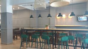 a restaurant with a large table and green chairs at Hotel Raglan in Mar del Plata