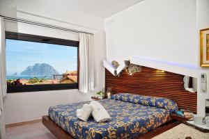 a bedroom with a bed and a large window at Residence L'Ea di Lavru - Appartamenti Mono-Bilo-Trilocali in Porto San Paolo