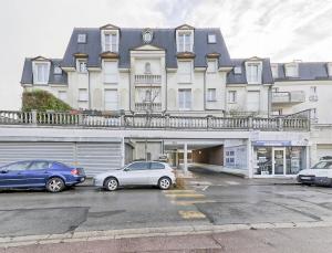 ein großes Gebäude mit Autos auf einem Parkplatz in der Unterkunft Le Marnois-Centre Ville in Noisy-le-Grand