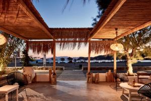 
a patio area with tables, chairs and umbrellas at Dionysos Seaside Resort Ios in Mylopotas
