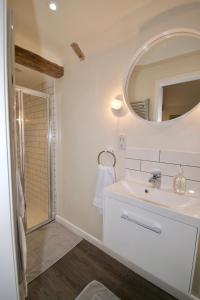 a white bathroom with a sink and a mirror at Fazeboon Cottages in Chillesford