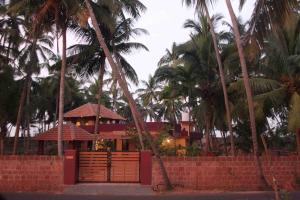 a house with palm trees and a brick wall at Vretreat in Kokkānisseri