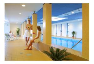 two women standing next to a swimming pool at Akzent Hotel Haus Surendorff in Bramsche