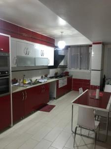uma cozinha com armários vermelhos e uma mesa em Coquelicot Tizi ouzou em Tizi Ouzou