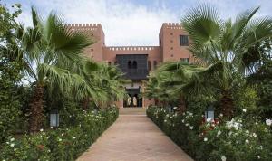 a building with palm trees and a walkway at Kasbah ATFEL in Ourika
