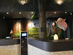 une statue de dinosaure assise au-dessus d'un comptoir dans l'établissement Henn na Hotel Laguna Ten Bosch, à Gamagori