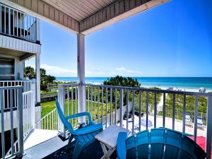 a porch with two blue chairs and the ocean at Beachside Hideout Unit K in Clearwater Beach