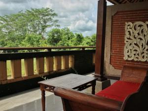 a balcony with a wooden table and bench on a balcony at Saren Indah Hotel in Ubud