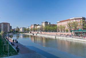 a river in a city with people walking along it at Sant'Ambrogio Elegance in Milan