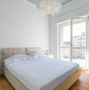 a white bedroom with a large bed and a window at Sant'Ambrogio Elegance in Milan