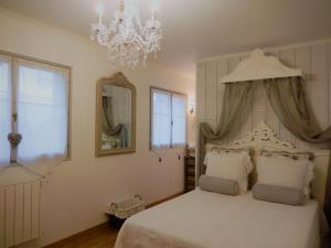 sypialnia z dużym białym łóżkiem z żyrandolem w obiekcie La Cordonnerie de Réau w mieście Réau