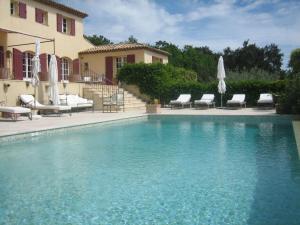 a swimming pool with chairs and umbrellas next to a house at Bastide Selva in La Garde-Freinet