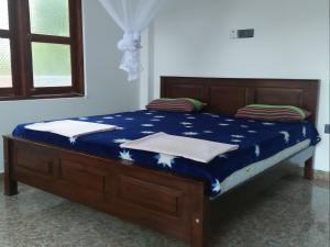 a bed in a room with a blue comforter at Charith Home Stay in Tangalle