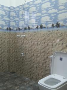 a bathroom with a toilet and a wall with a beach at Charith Home Stay in Tangalle