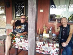two men sitting at a table in front of a house at Rim Than View Resort in Ubon Ratchathani