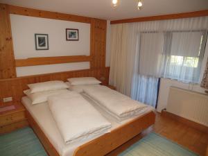 Un dormitorio con una cama con almohadas blancas y una ventana en Beilelers Hof, en Arzl im Pitztal
