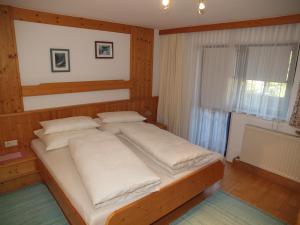 a bedroom with a bed with white pillows and a window at Beilelers Hof in Arzl im Pitztal