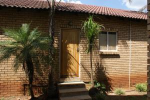 a brick house with a brown door and a window at Eric's Apartments in Centurion