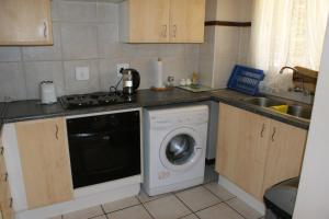a kitchen with a washing machine and a sink at Eric's Apartments in Centurion
