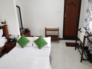 a white couch with two green pillows in a room at The Grand Bandarawela in Bandarawela