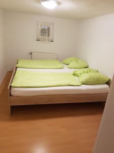 a bed in a room with green sheets and pillows at Schöne, private Wohnungen in Aalen