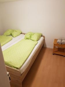a bed with green sheets and pillows in a room at Schöne, private Wohnungen in Aalen