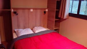 una camera con un letto con una coperta rossa di Camping de l'Arche a Lanas