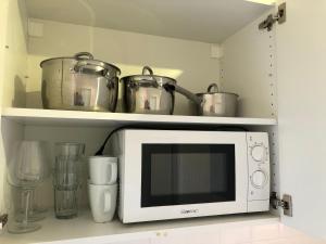 a microwave on a shelf with pots and pans at Appartement Redhouse in Regensburg